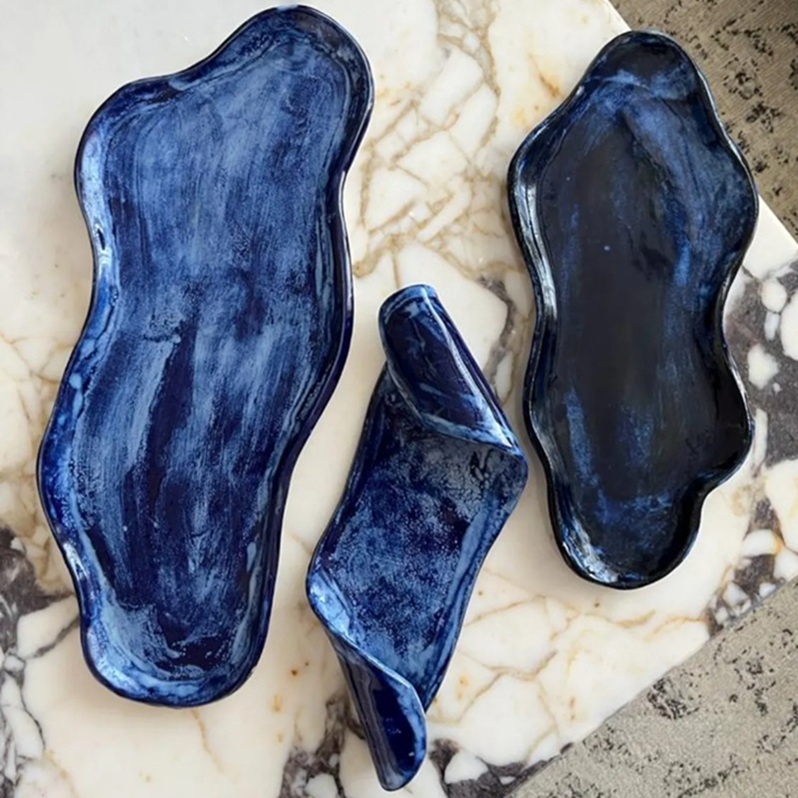 Indigo irregular ceramic tray set (3 pieces) — handcrafted organic shapes with deep blue/black glaze, displayed on white marble surface