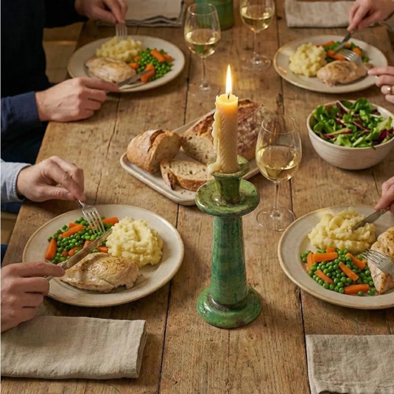 Vintage green crackle ceramic candle holder (with lit candle) as a dining table centerpiece, surrounded by plates of food and wine glasses
